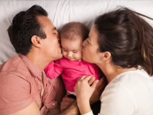 Parents kissing their baby's cheeks together