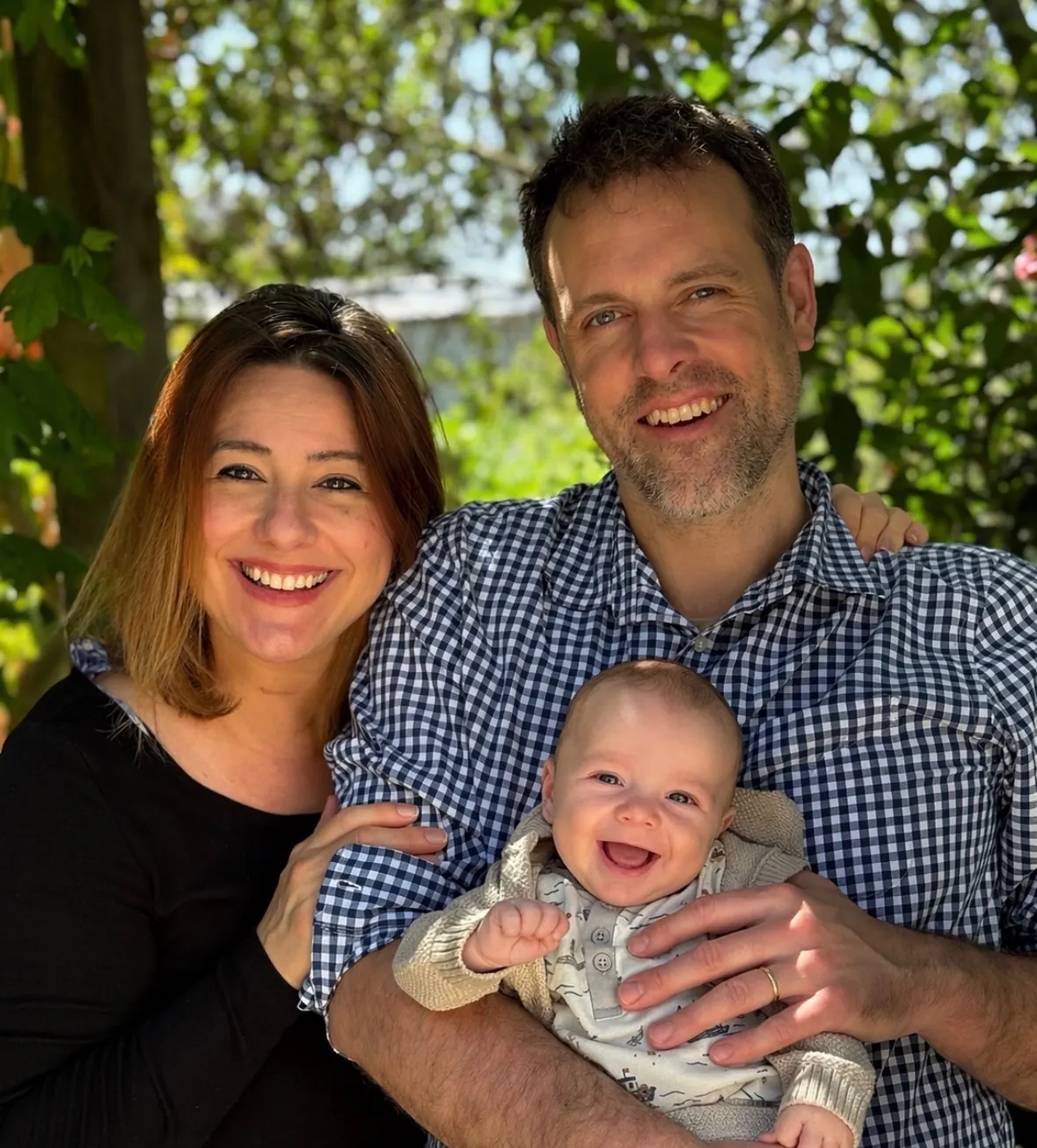 A young couple holding their smiling baby outdoors
